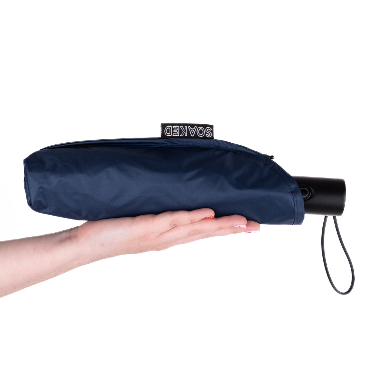 Hand holding the SOAKED Atlantic navy umbrella in its waterproof sleeve made from recycled plastic