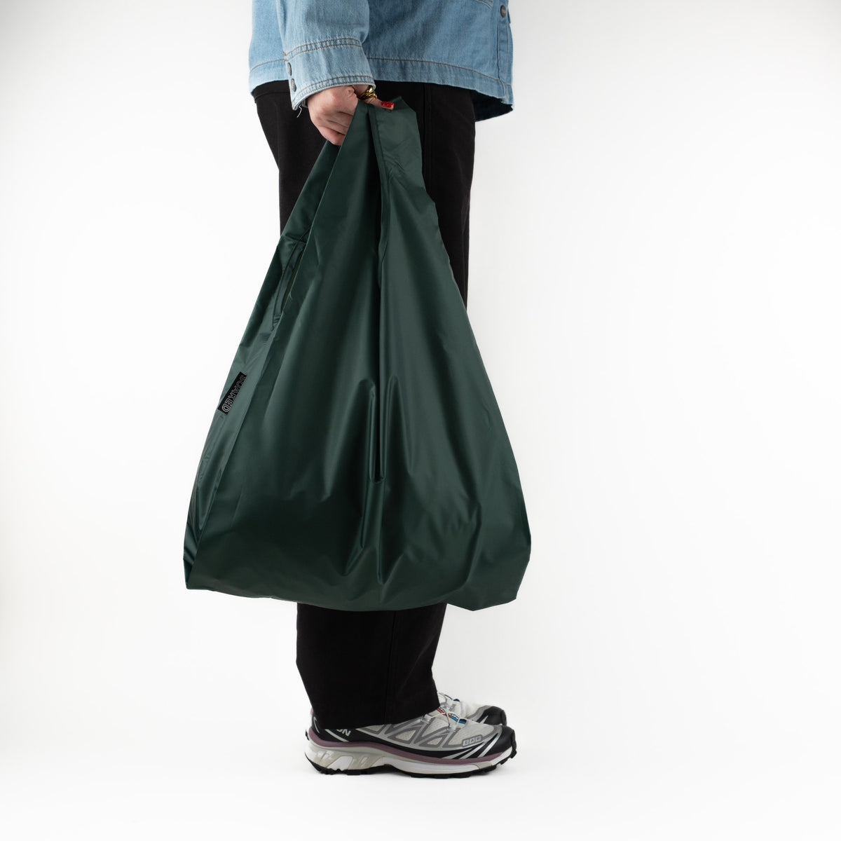 Person standing side-on with the SOAKED Big Sur forest green tote bag