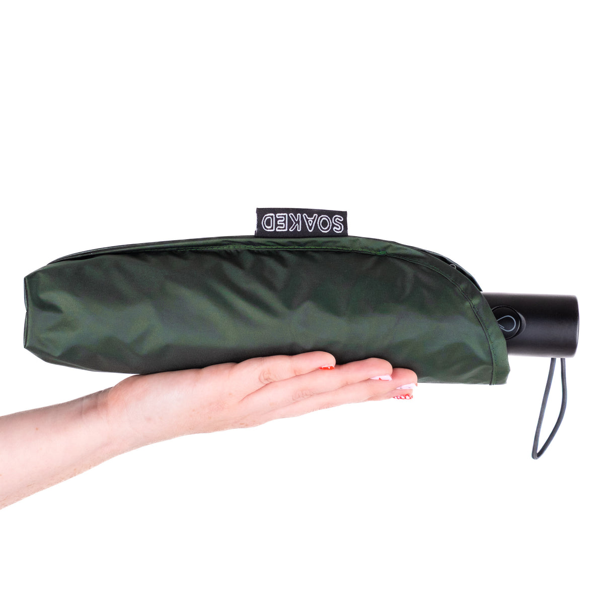 Hand holding the SOAKED Big Sur forest green umbrella in its waterproof sleeve made from recycled plastic