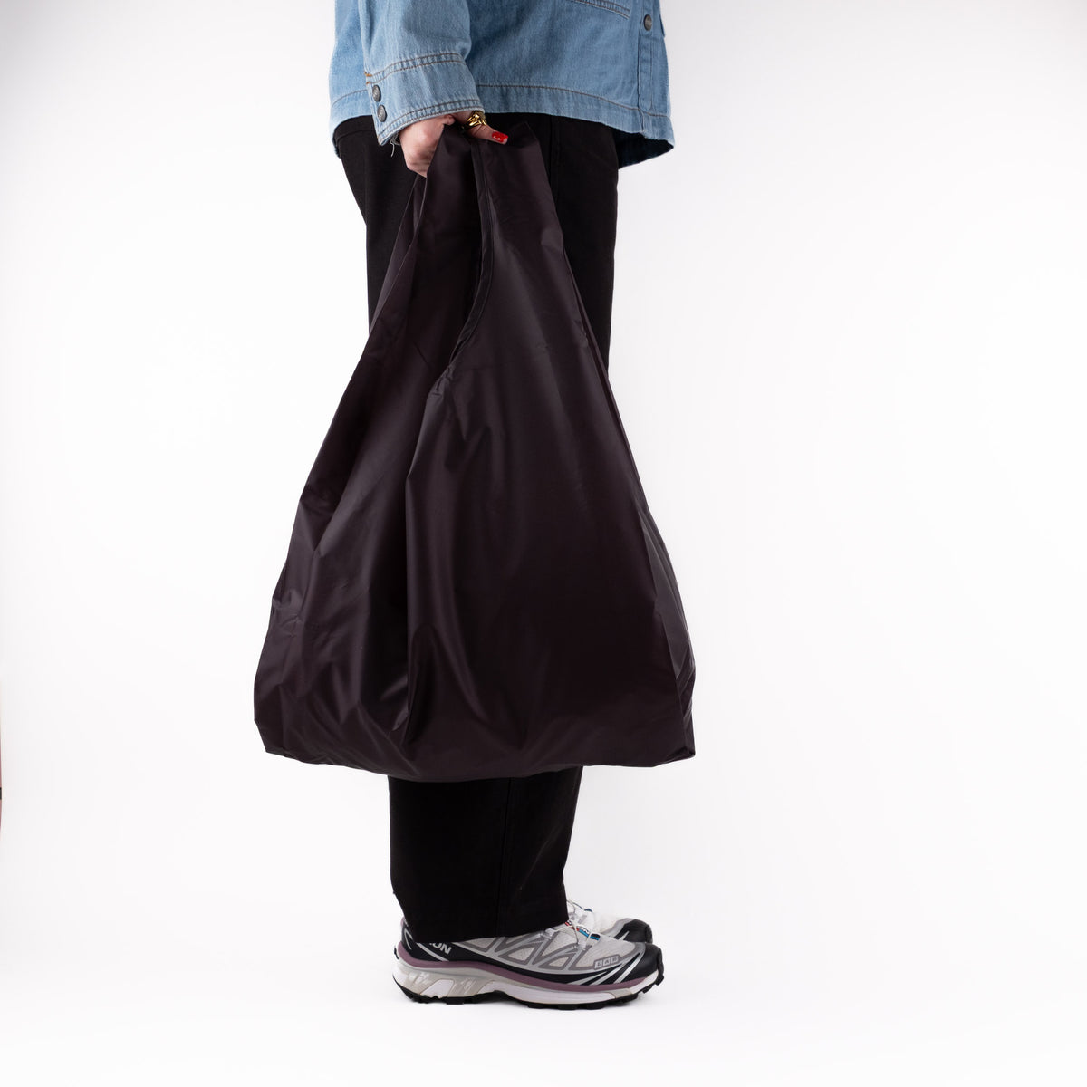 Person standing side-on with the SOAKED Dark Skies black tote bag, showing the side gussets