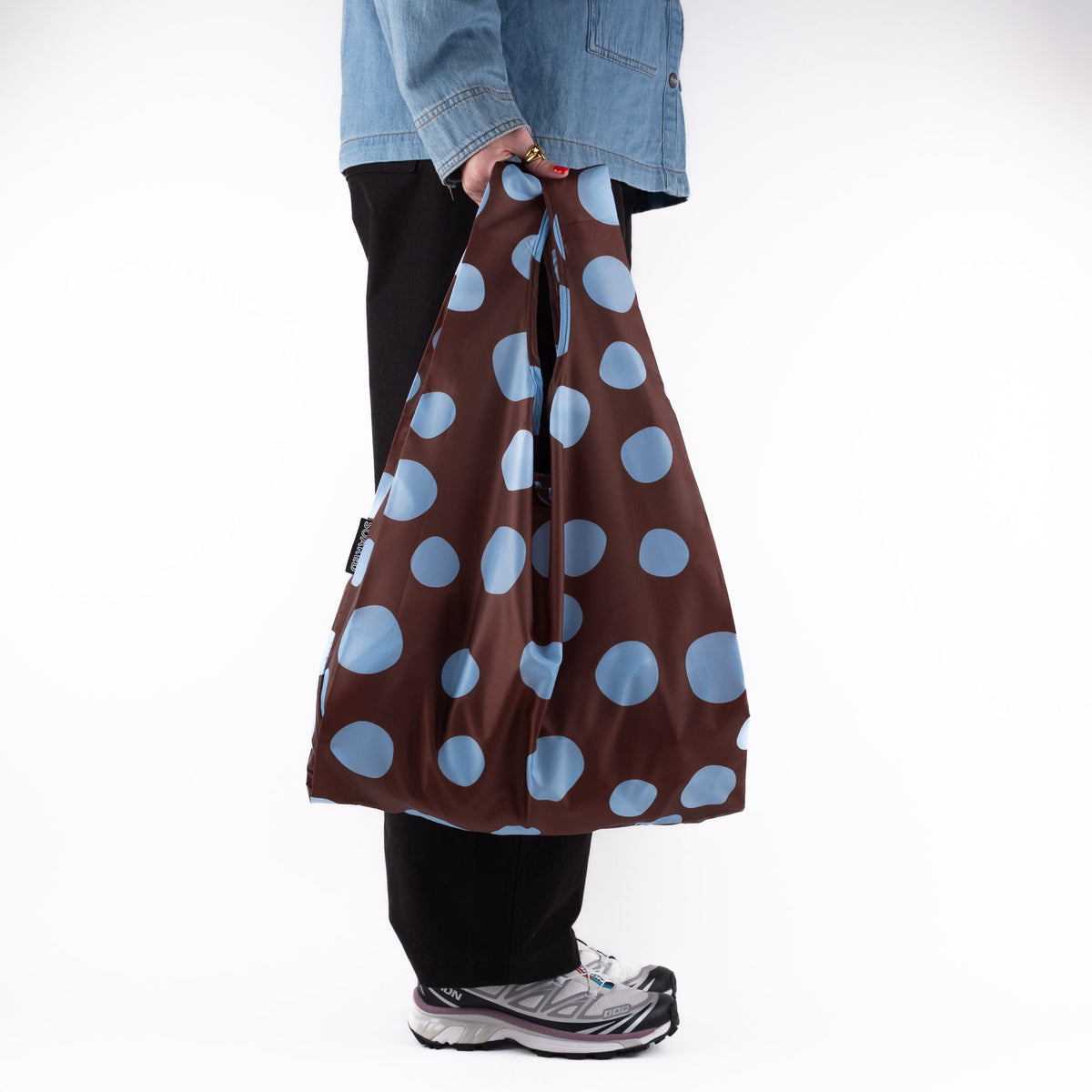Person standing side-on with the SOAKED Polka brown and sky blue polka dot tote bag