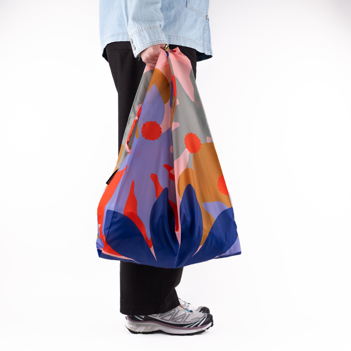 Person standing side-on with the SOAKED Superbloom bold floral tote bag