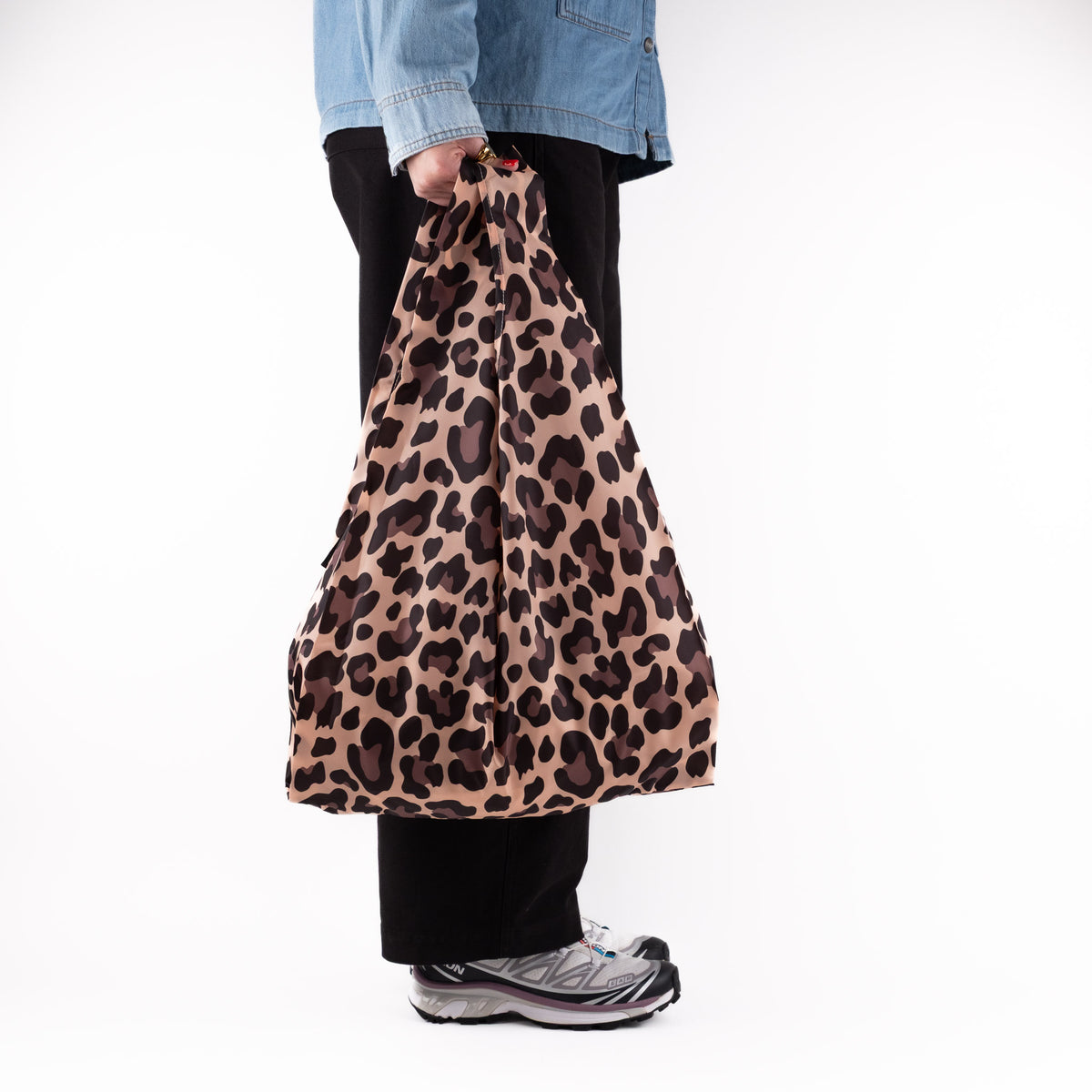 Person standing side-on with the SOAKED Wild Thing leopard print tote bag, showing the side gussets
