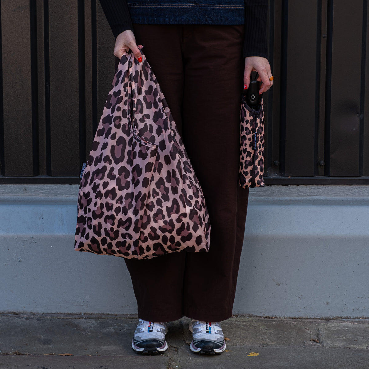 Person standing outside holding the SOAKED Wild Thing leopard print tote bag open and the umbrella in its sleeve